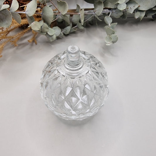 Small round vintage clear glass trinket box with diamond-faceted pattern and lid.