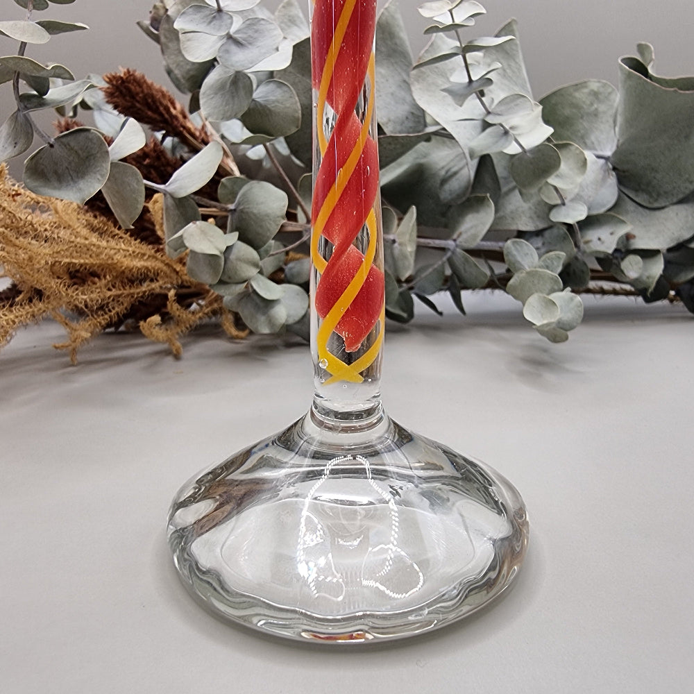 Murano-style glass candle holder with red swirl stem and clear top.
