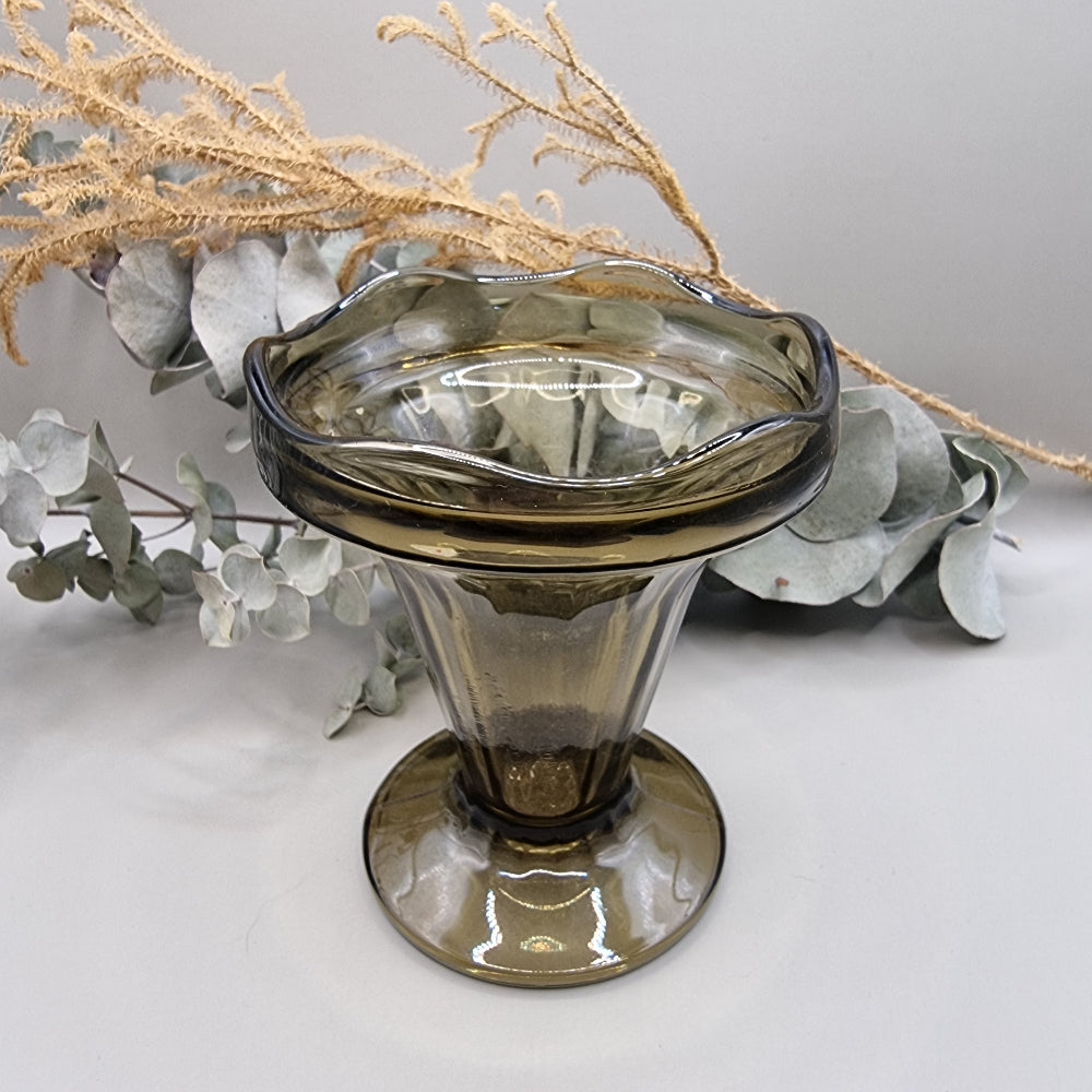 Smoky grey pedestal glass vase with fluted shape and wavy rim.