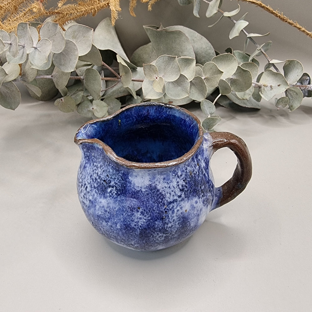 Small handmade pottery jug with cobalt blue glaze and brown handle