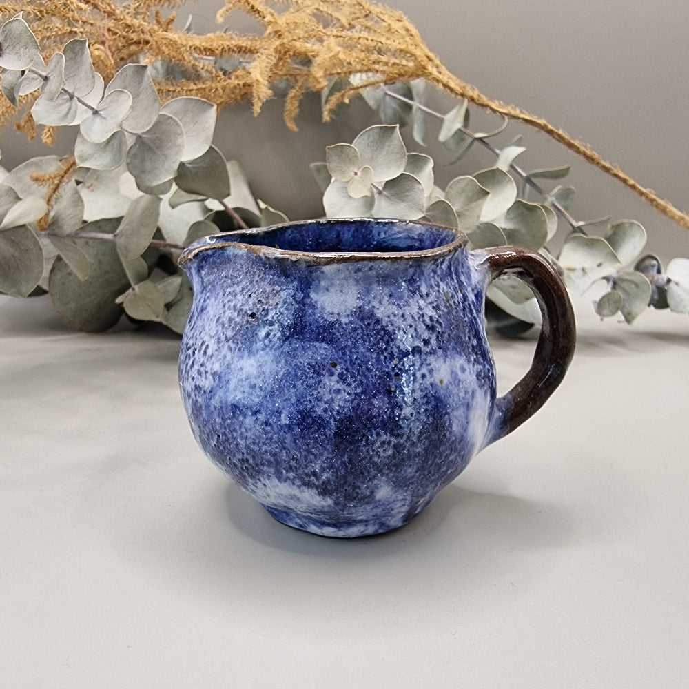 Small handmade pottery jug with cobalt blue glaze and brown handle