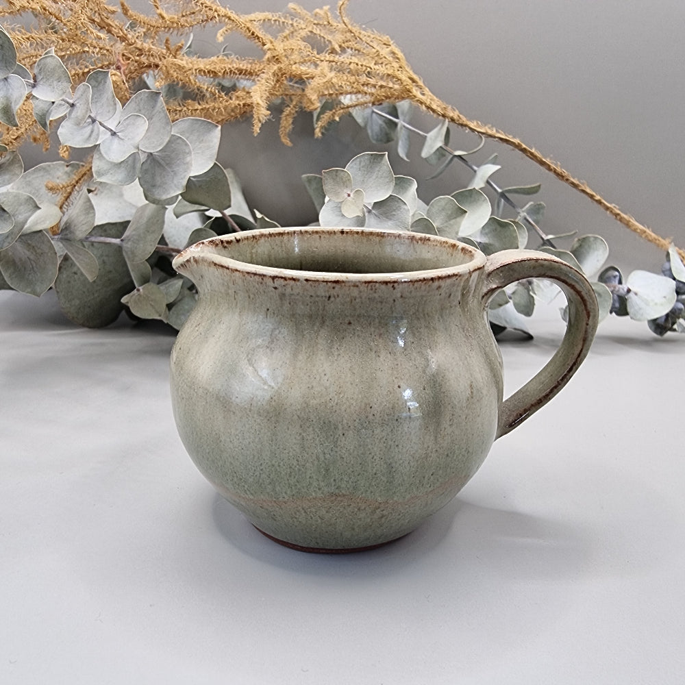 Handmade green studio pottery jug with handle and spout