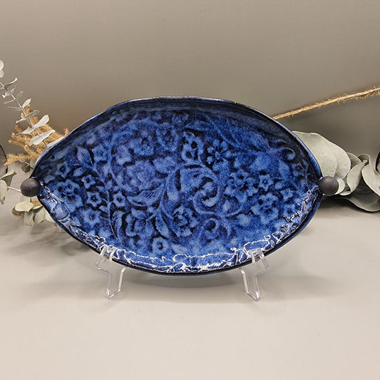 Deep blue ceramic dish with embossed floral pattern and round end handles.