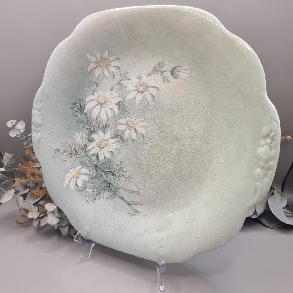 Pale green ceramic plate with hand-painted white daisies, scalloped edge, and vintage finish.