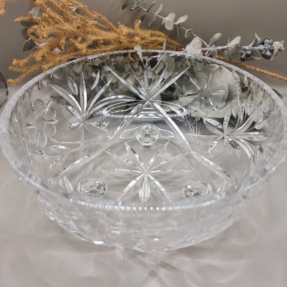 Clear footed glass bowl with starburst and floral cut-style patterns.