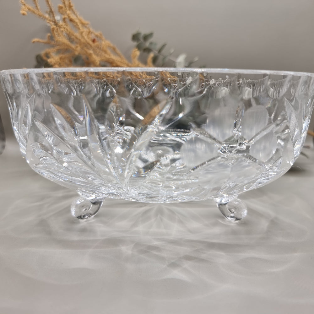 Clear footed glass bowl with starburst and floral cut-style patterns.