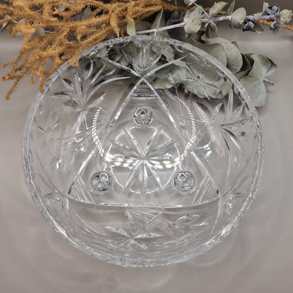 Clear footed glass bowl with starburst and floral cut-style patterns.