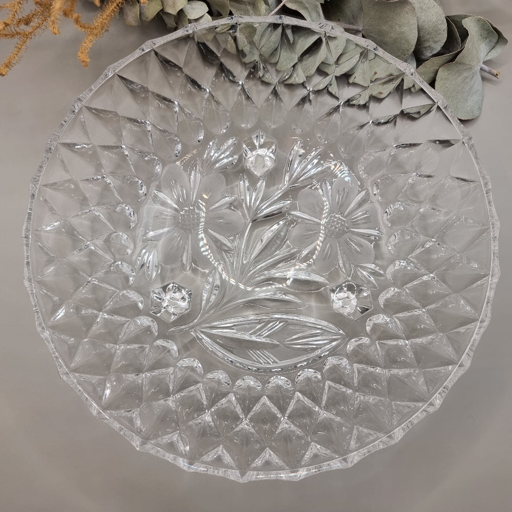Pressed glass bowl with floral centre, diamond pattern, and three-footed base.