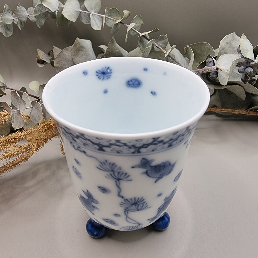 Footed Japanese porcelain sake cup with blue and white goldfish and lotus design.