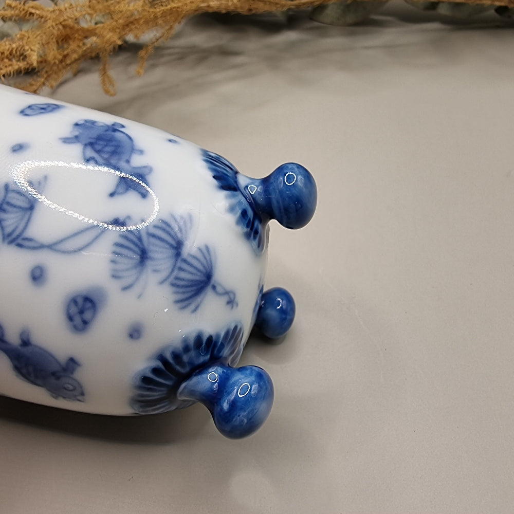 Footed Japanese porcelain sake cup with blue and white goldfish and lotus design.