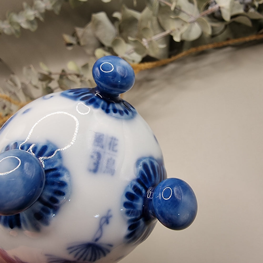 Footed Japanese porcelain sake cup with blue and white goldfish and lotus design.