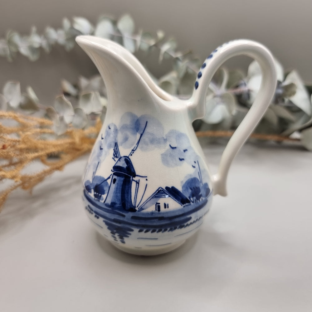 Small Delft porcelain jug with hand-painted blue windmill and house scene.