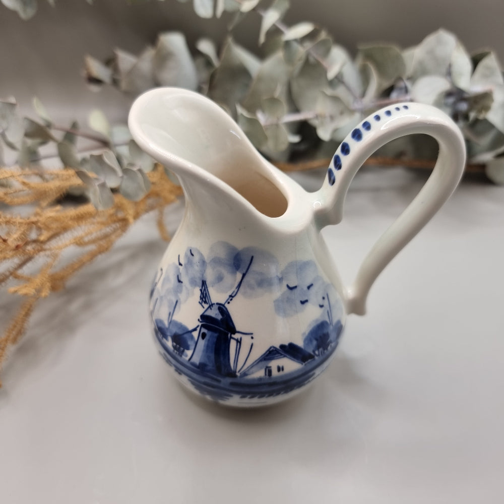 Small Delft porcelain jug with hand-painted blue windmill and house scene.