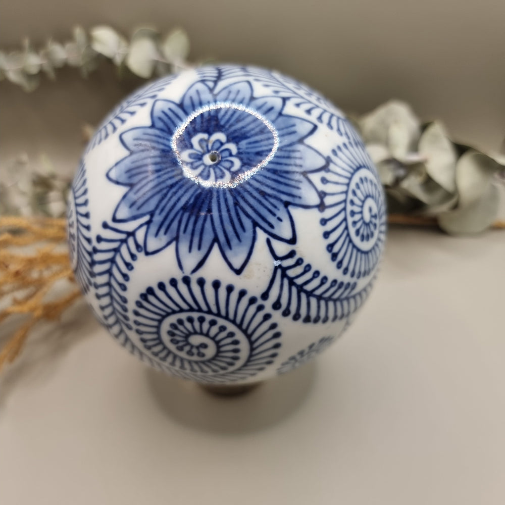 Blue and white ceramic sphere with spiral and floral patterns, decorative orb.