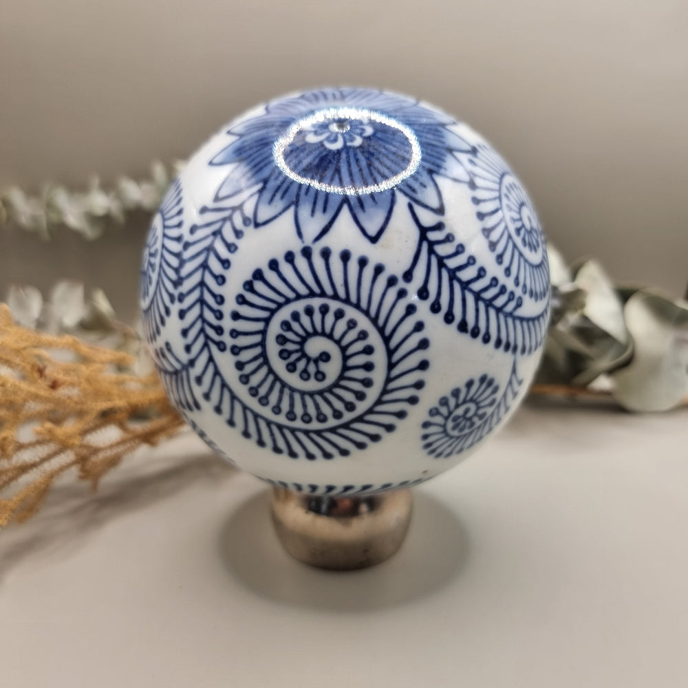 Blue and white ceramic sphere with spiral and floral patterns, decorative orb.