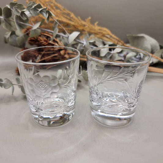 Pair of cut crystal shot glasses with etched floral and leaf pattern.