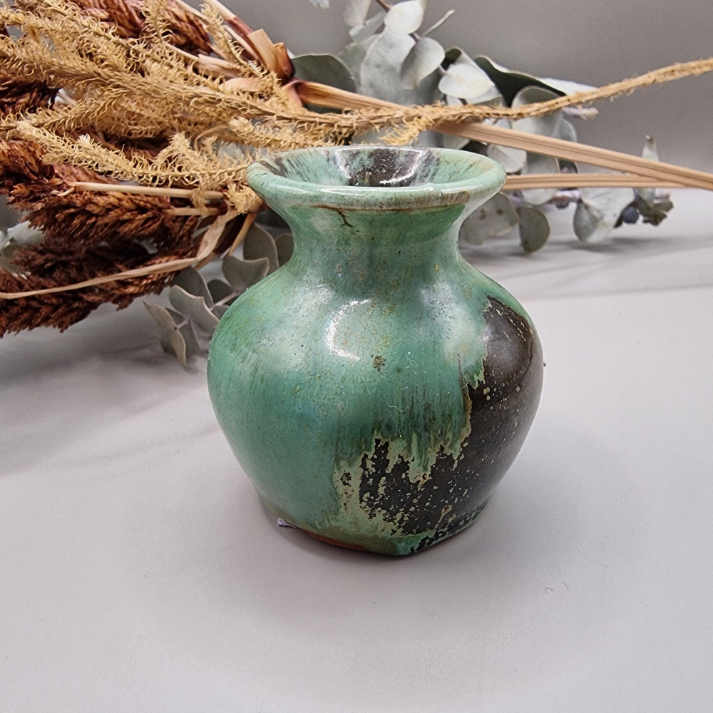 Small green glazed studio pottery vase with rustic brown accents.