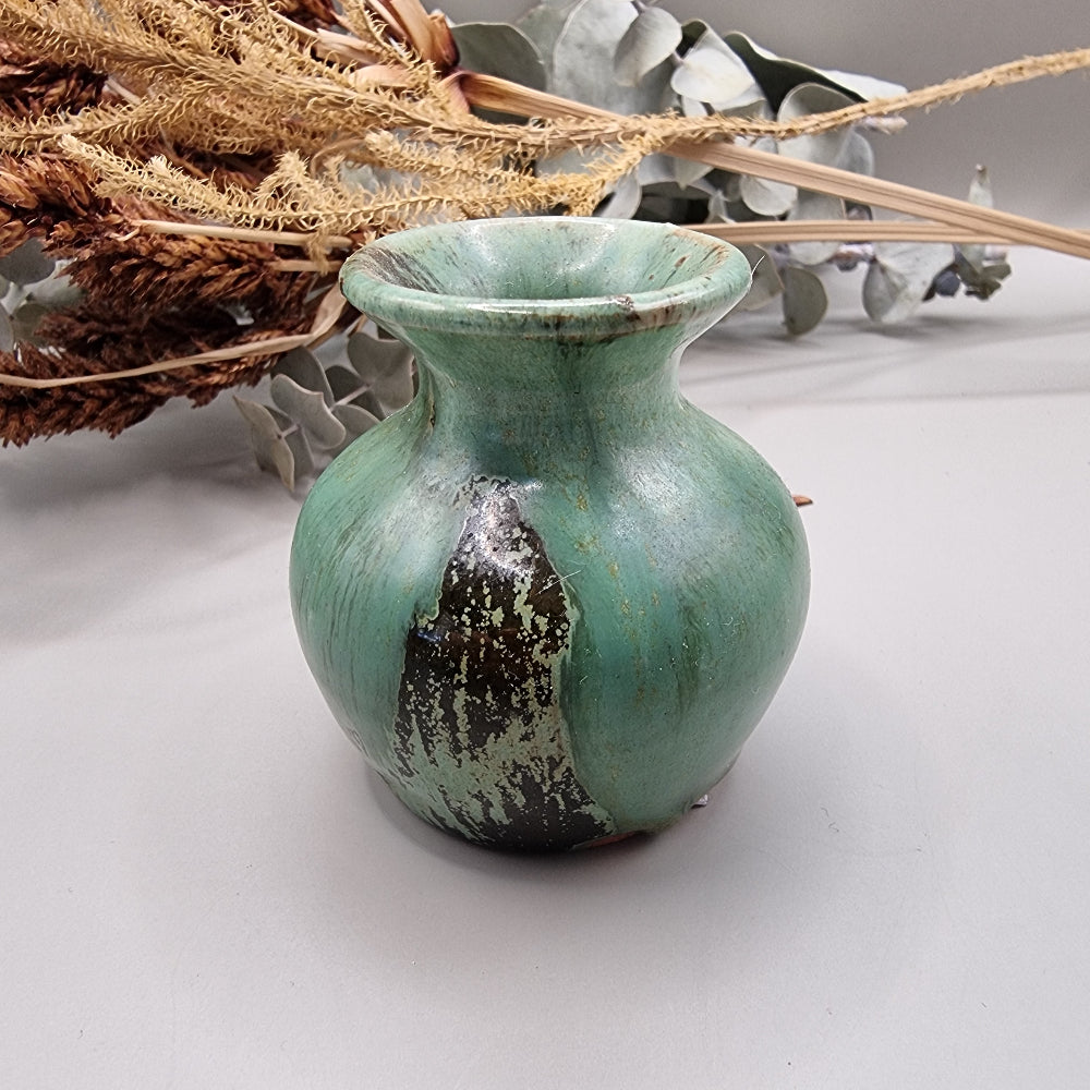 Small green glazed studio pottery vase with rustic brown accents.