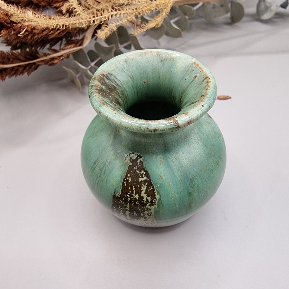 Small green glazed studio pottery vase with rustic brown accents.