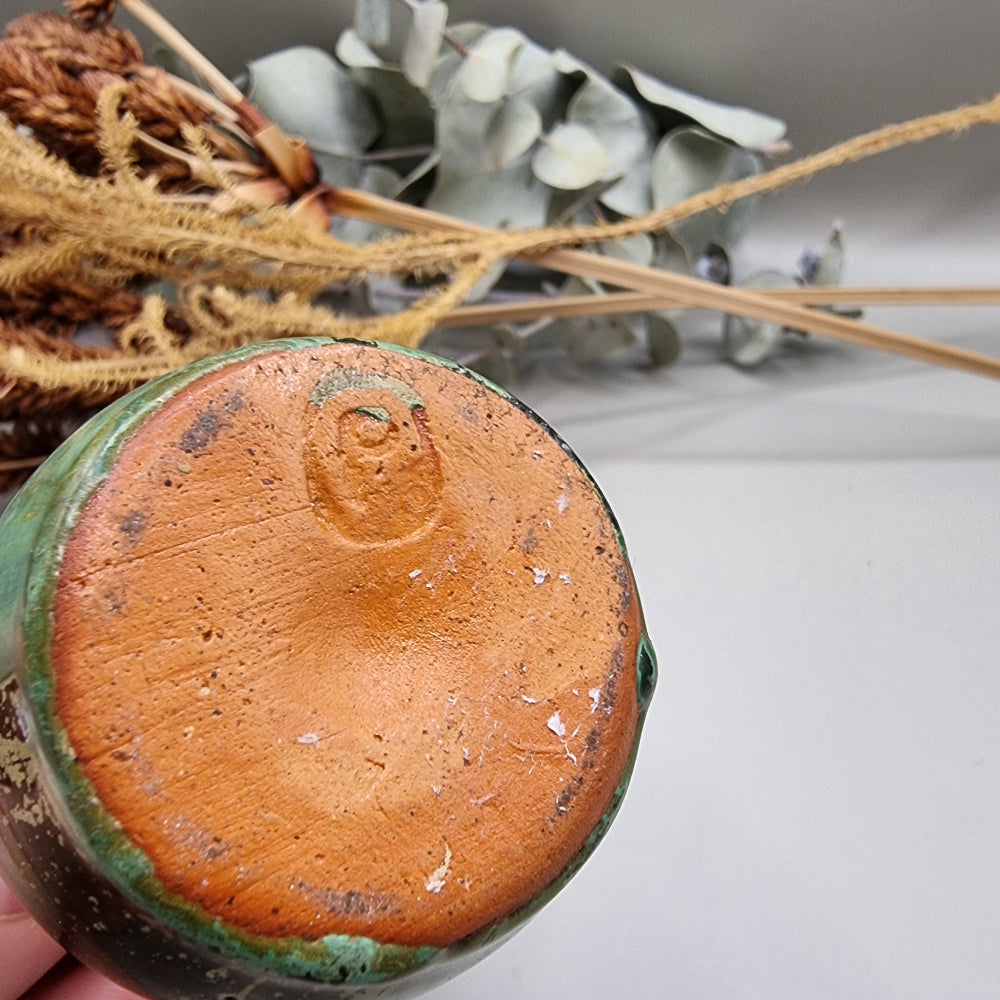 Small green glazed studio pottery vase with rustic brown accents.