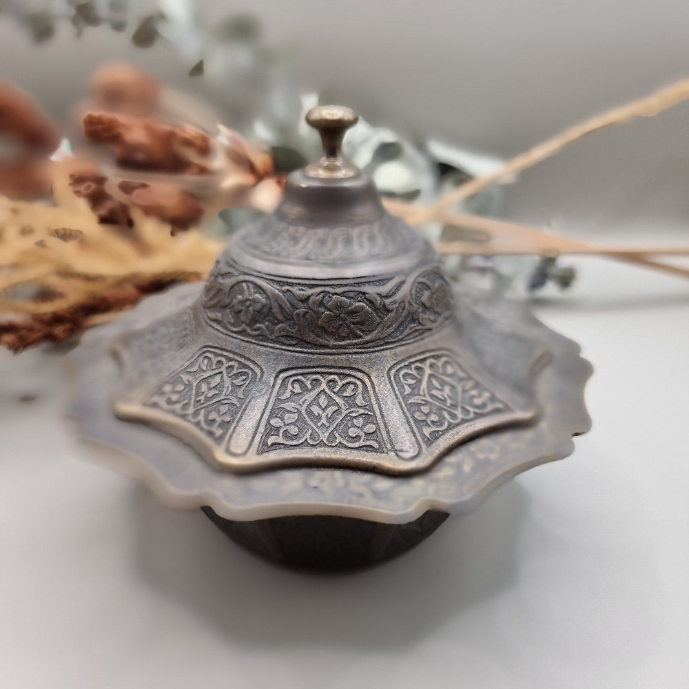 Ornate silver and gold-toned lidded metal trinket dish with embossed patterns.