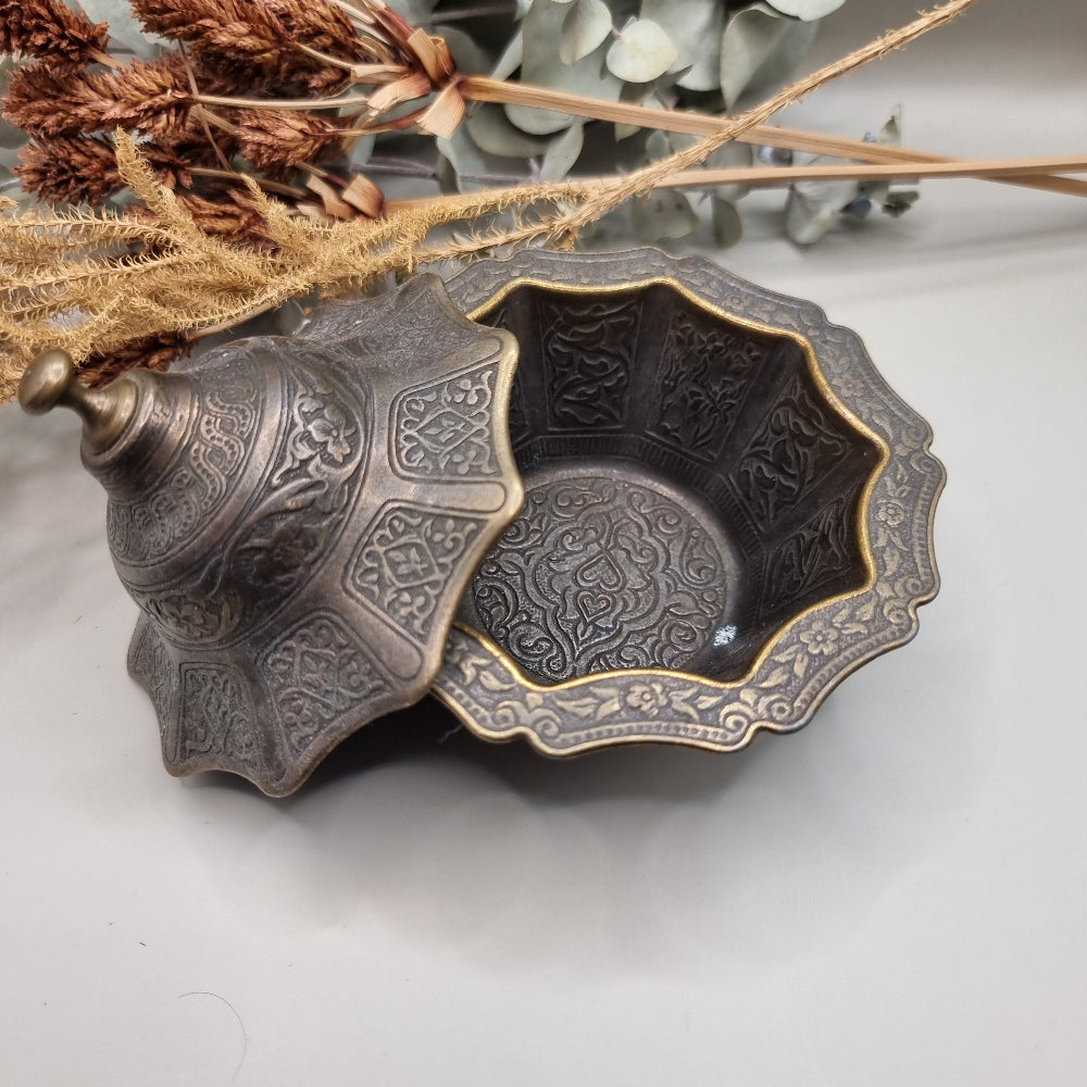 Ornate silver and gold-toned lidded metal trinket dish with embossed patterns.