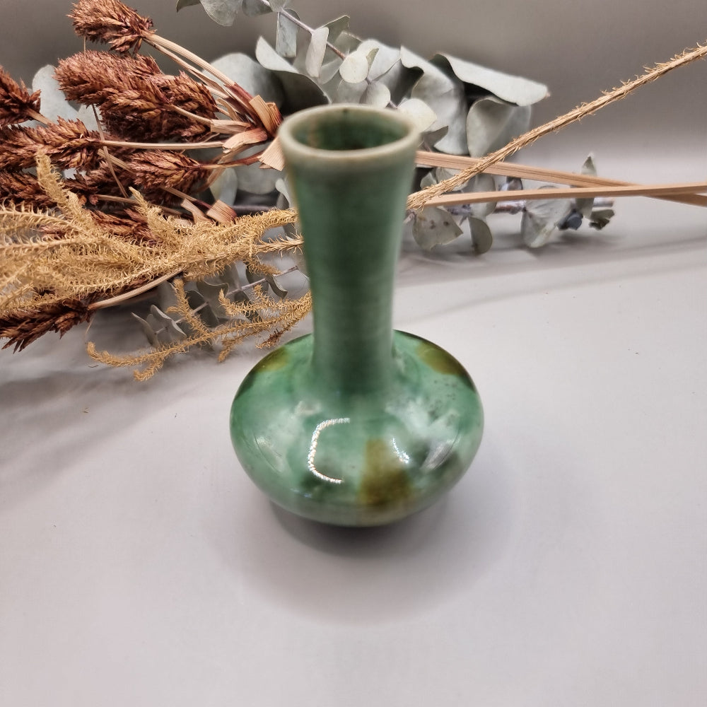 Small handmade green bud vase with narrow neck and rounded base.