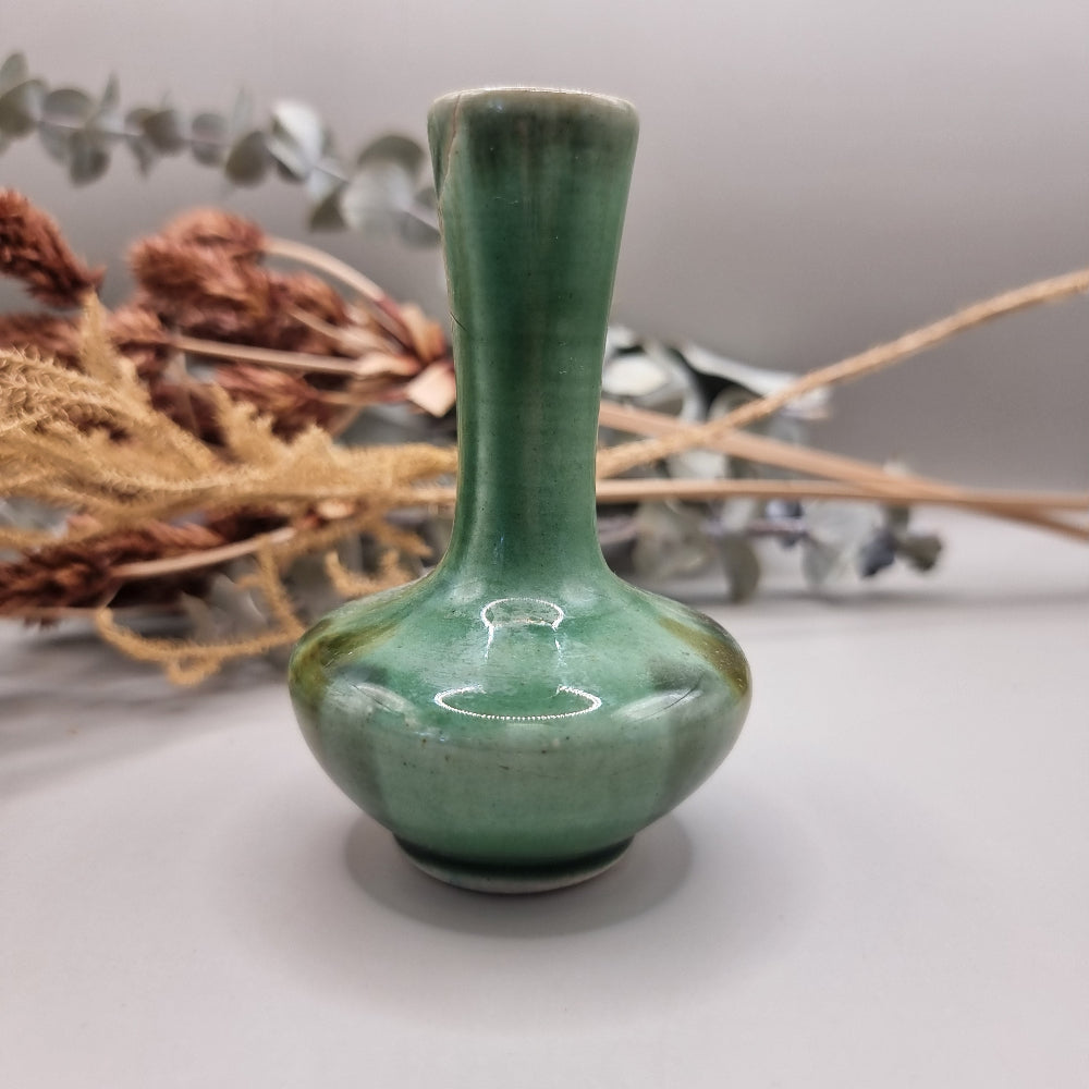 Small handmade green bud vase with narrow neck and rounded base.
