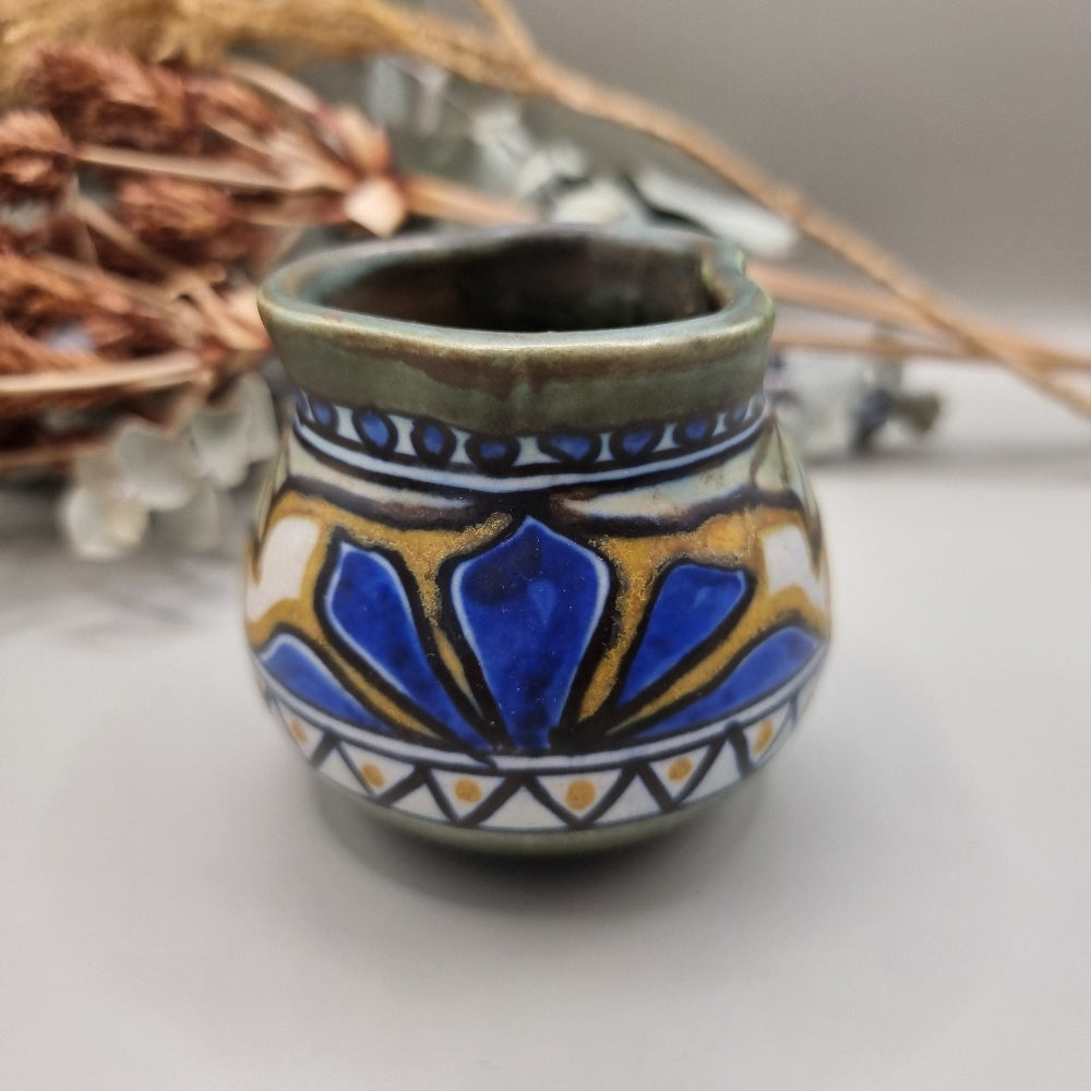Small hand-painted ceramic pot with blue, gold, and green decorative pattern.