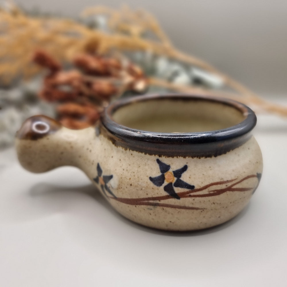Small speckled soup bowl with painted floral vine and handle.