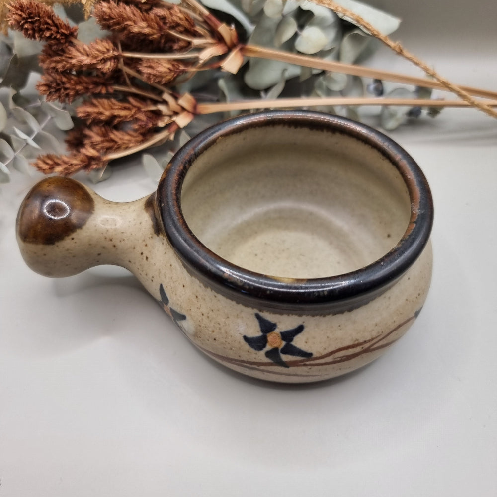 Small speckled soup bowl with painted floral vine and handle.