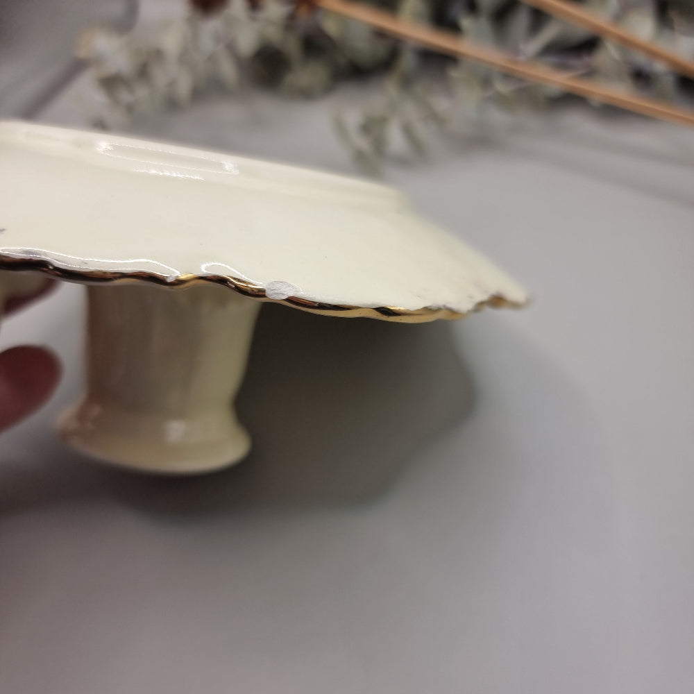 Cream ceramic candle holder with fern design, gold trim, and dotted handle