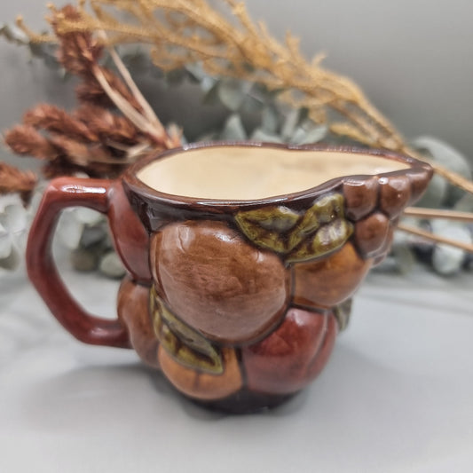 Vintage ceramic jug with raised fruit motif and brown glazed finish