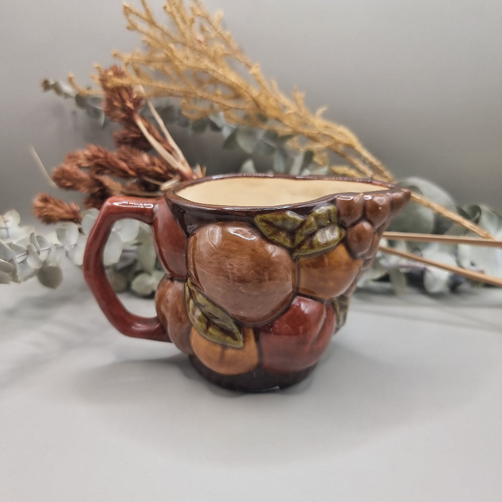 Vintage ceramic jug with raised fruit motif and brown glazed finish
