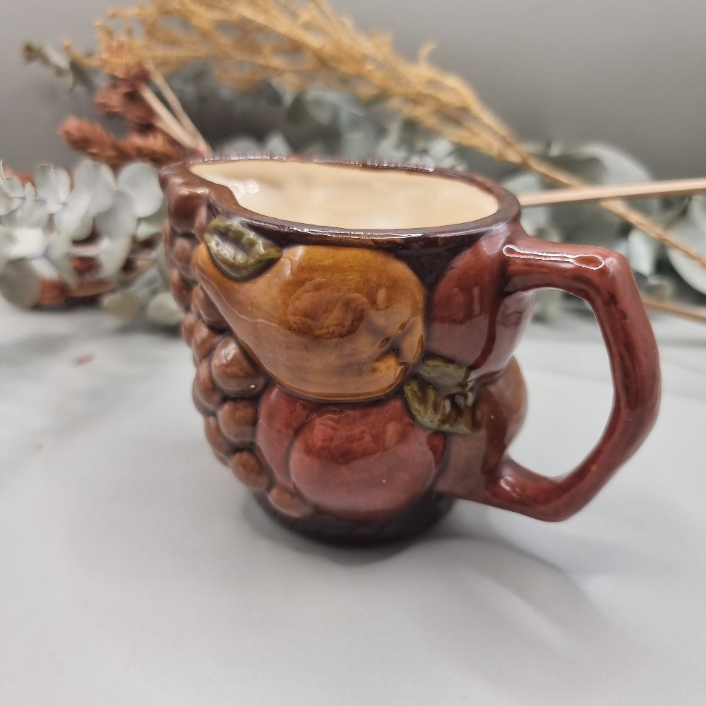 Vintage ceramic jug with raised fruit motif and brown glazed finish