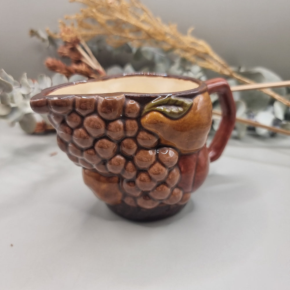 Vintage ceramic jug with raised fruit motif and brown glazed finish