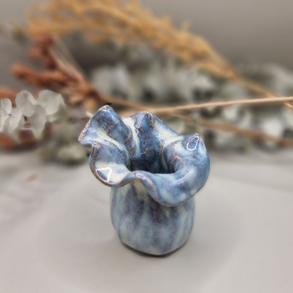 Small blue handmade pottery vase with ruffled rim and marbled glaze pattern.