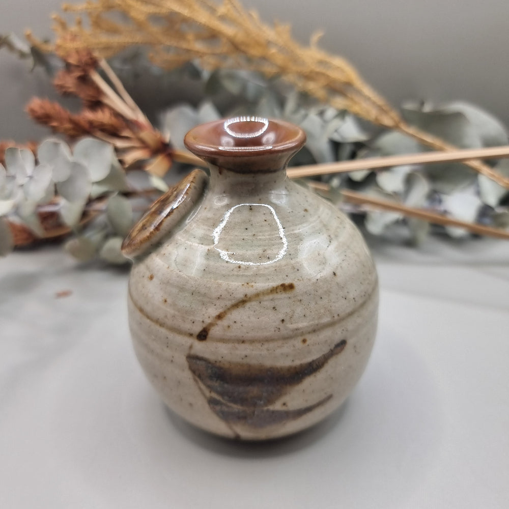 Vintage Norfolk Island pottery vase with speckled glaze and brushstroke detail.