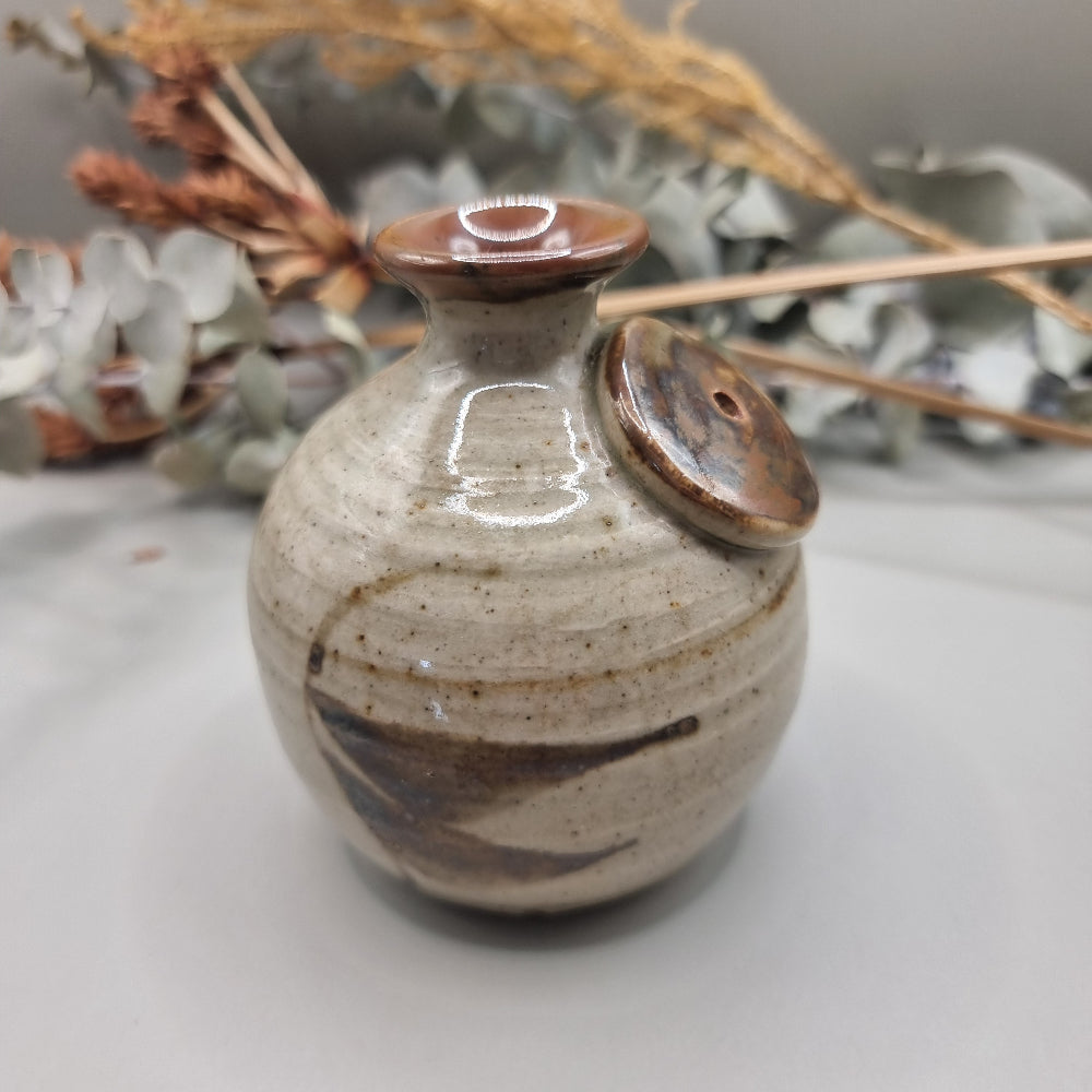 Vintage Norfolk Island pottery vase with speckled glaze and brushstroke detail.