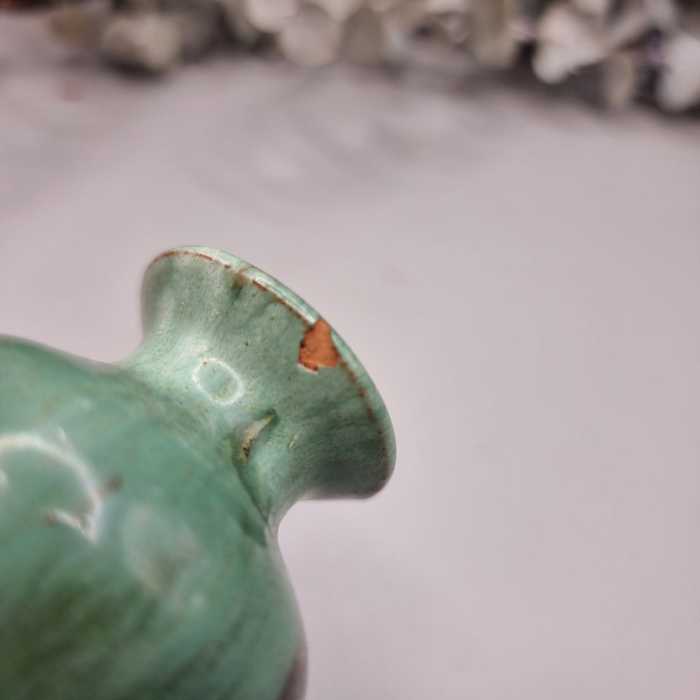 Small green glazed studio pottery vase with rustic brown accents.