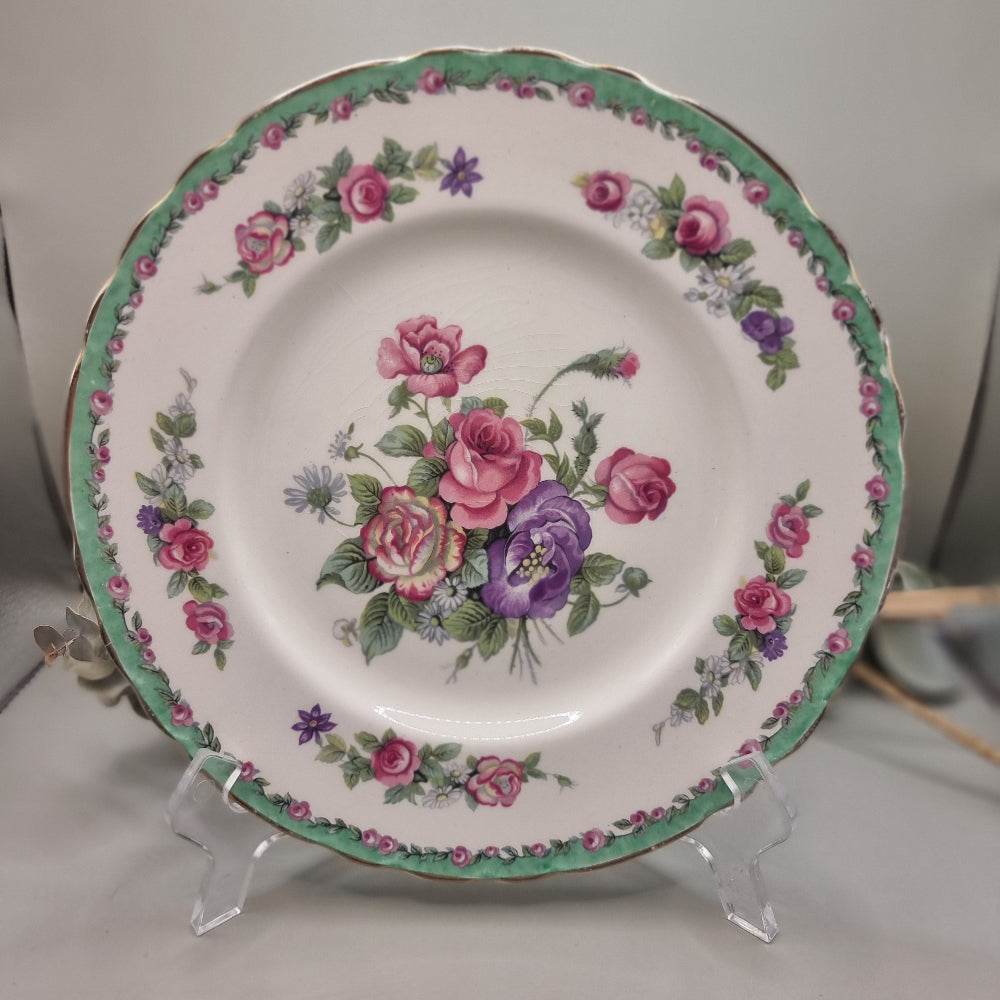 Royal Staffordshire “Nancy” plate by Clarice Cliff with green rim, floral border and central pink and purple rose bouquet.