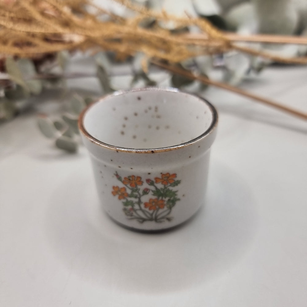 Mini speckled ceramic pot with orange floral design and bronze rim.