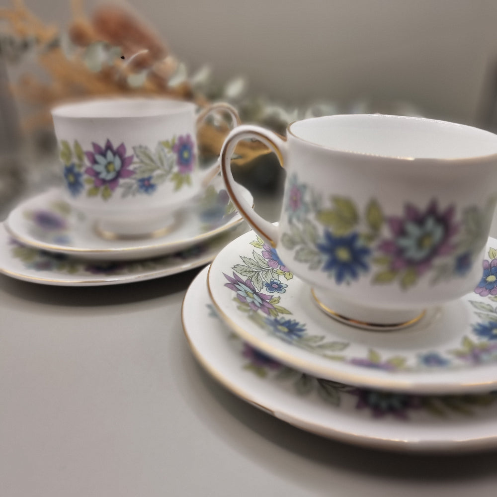 Two Paragon Cherwell bone china trios with soft floral design and gold rim.