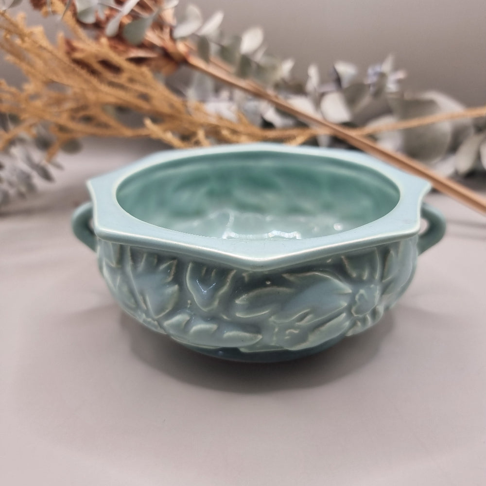 Pale teal ceramic bowl with embossed floral pattern and side handles