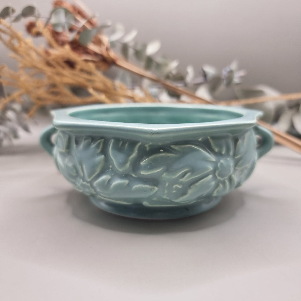 Pale teal ceramic bowl with embossed floral pattern and side handles