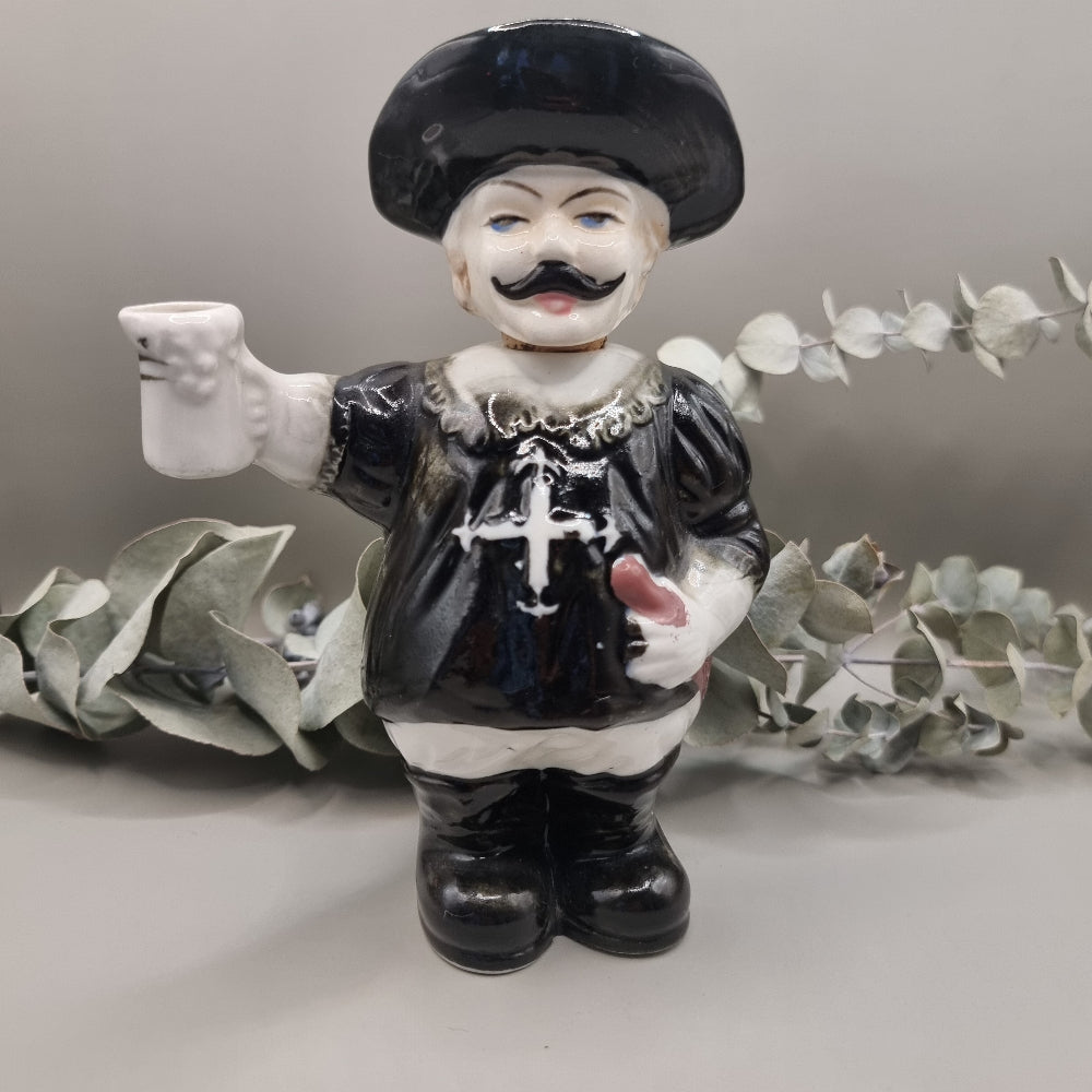 Vintage ceramic musketeer decanter holding a sword and stein with cork stopper and feathered hat.