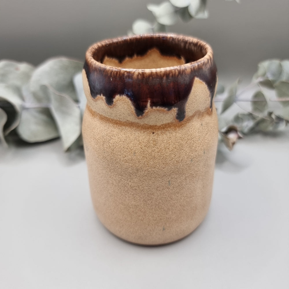 Studio pottery jar with sandy matte base and brown drip glaze rim