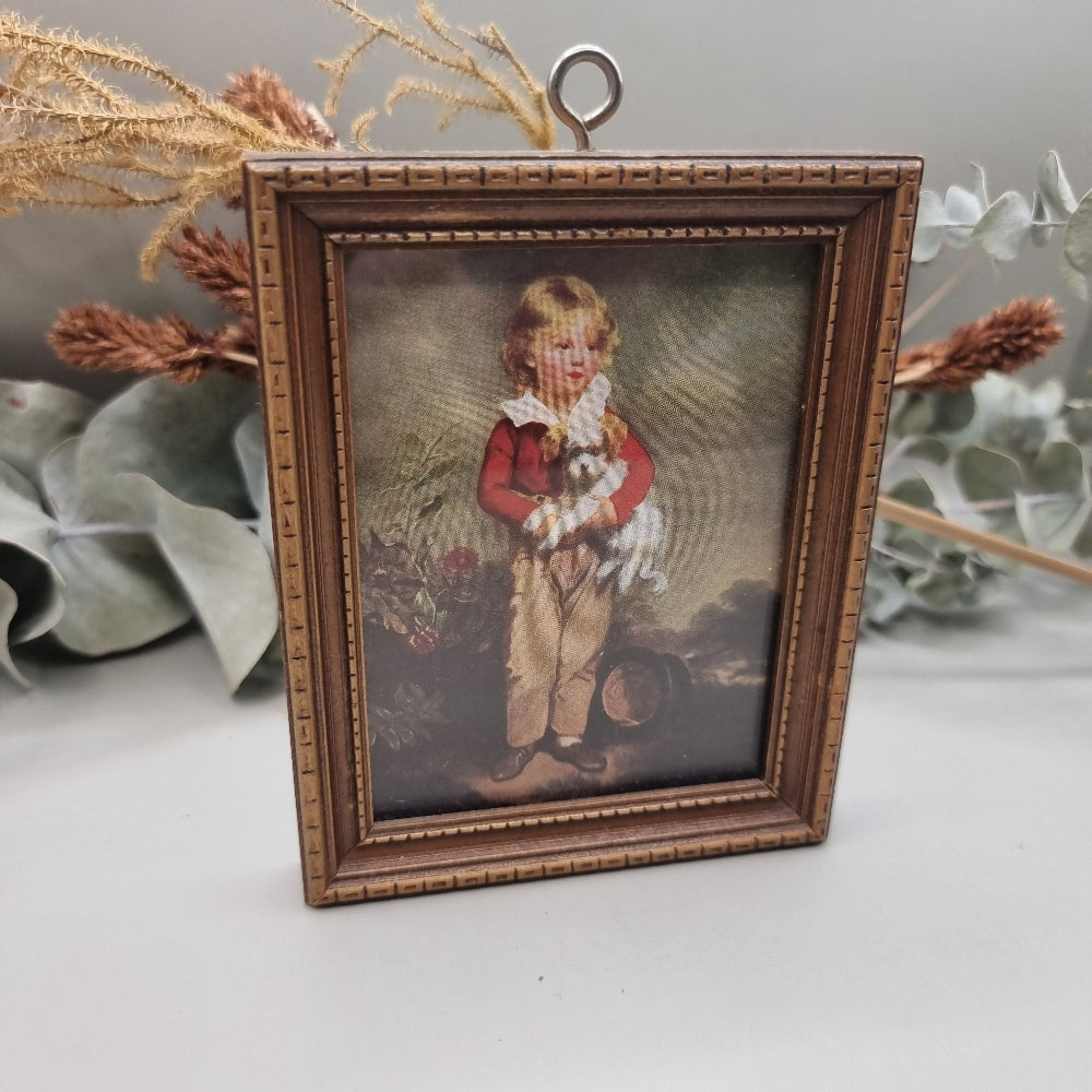Framed vintage print of young boy in red coat holding a small white dog