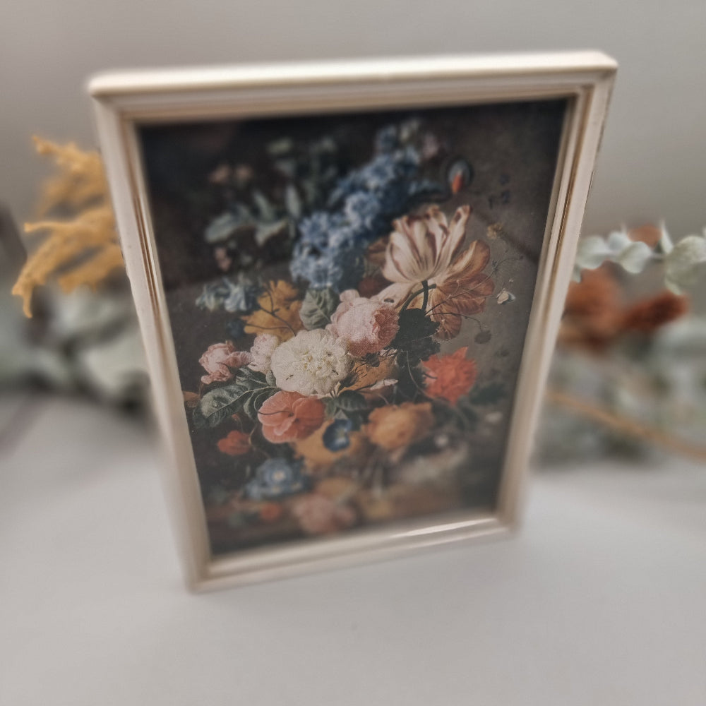 Vintage floral still life print in cream-toned frame with colourful bouquet.