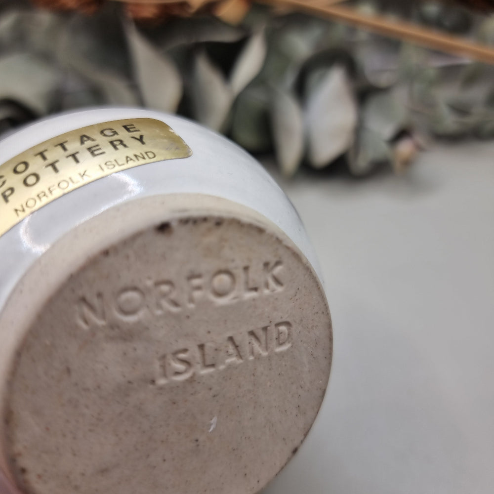 Norfolk Island pottery cup with pine tree design and blue rim